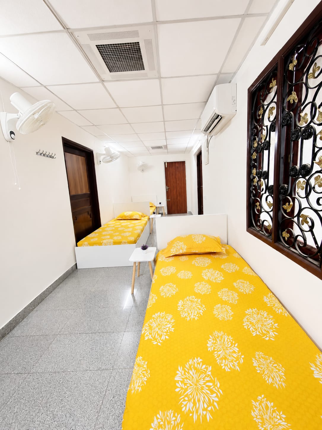 Bright 3-sharing room at GridLiv with marigold bedding, AC and wall fans